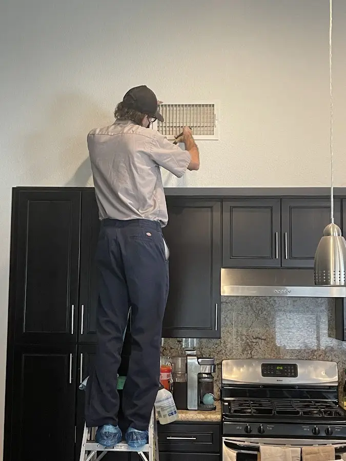 Technician inspecting an air vent during HVAC service in Lloyd